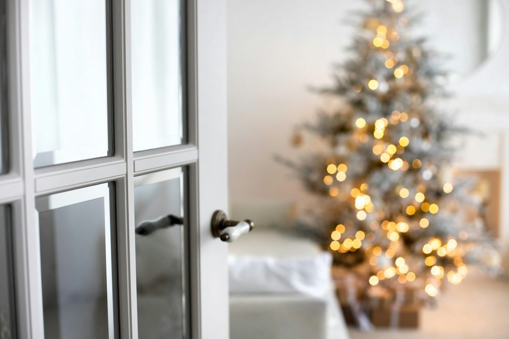 Selective focus on door. Blured background christmas lights. Open door in home minimalistic interior